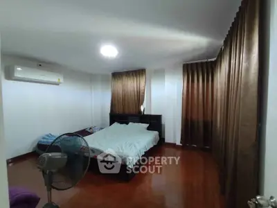 Spacious bedroom with wooden flooring and large windows for natural light.