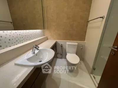 Modern bathroom with sleek sink and toilet, featuring elegant tile design and ample lighting.