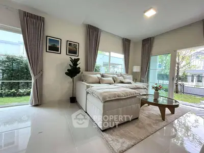 Spacious living room with modern decor and large windows offering garden views.