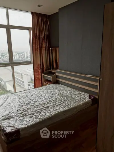 Cozy bedroom with large window offering city view and modern furnishings.