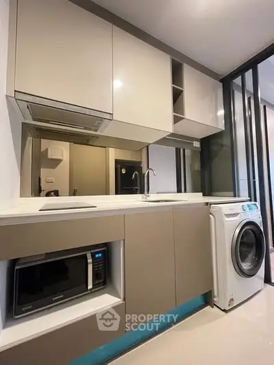 Modern kitchen with sleek cabinetry, built-in microwave, and washing machine in a compact layout.