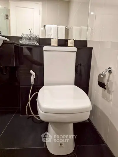 Modern bathroom with sleek black and white design featuring a contemporary toilet and stylish fixtures.