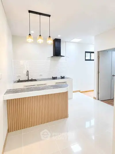 Modern kitchen with sleek design and open layout, featuring stylish pendant lights and gas stove.