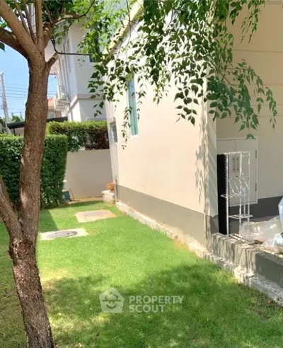 Charming garden area with lush green lawn and tree shade, perfect for outdoor relaxation.