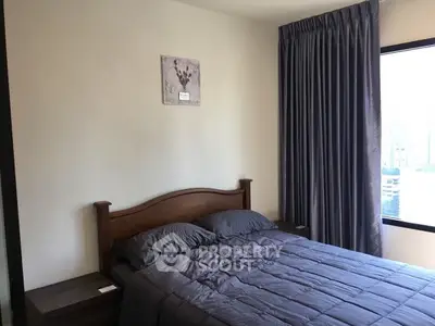 Cozy bedroom with modern decor and large window offering city views.