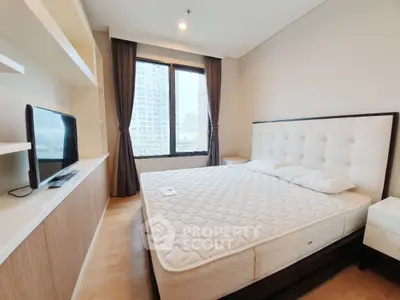 Spacious bedroom with large window and modern furnishings in urban apartment