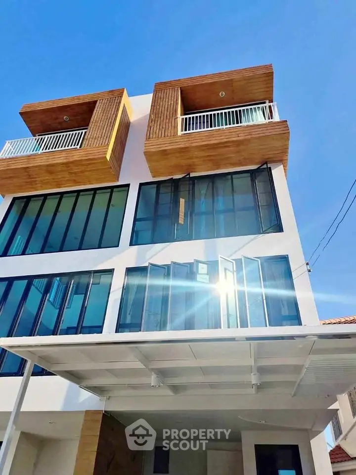 Modern architectural building with large glass windows and wooden accents under a clear blue sky.