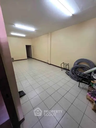 Spacious tiled room with fluorescent lighting, ideal for storage or office use.