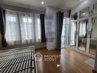 Spacious bedroom with large windows and mirrored closet doors