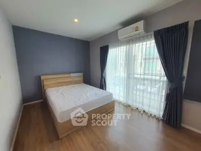 Spacious bedroom with wooden flooring and large window for natural light