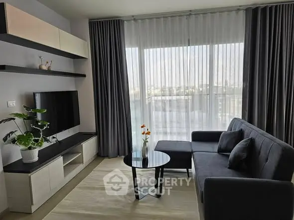Modern living room with sleek furniture and large window offering natural light.