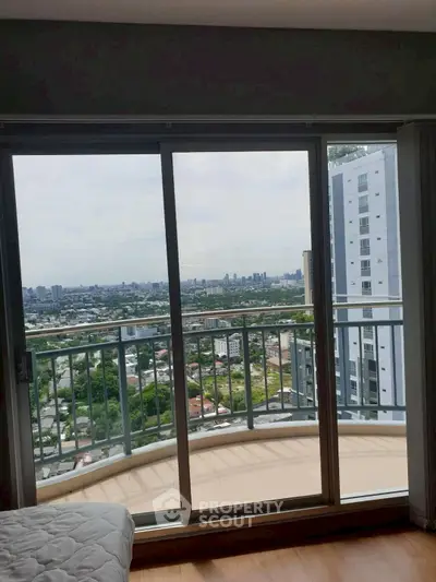 Stunning high-rise balcony view overlooking cityscape and lush greenery.