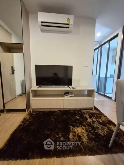 Modern living room with sleek TV setup and air conditioning in a stylish apartment.