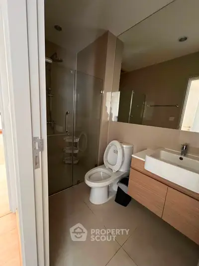 Modern bathroom with glass shower and sleek vanity in contemporary apartment.