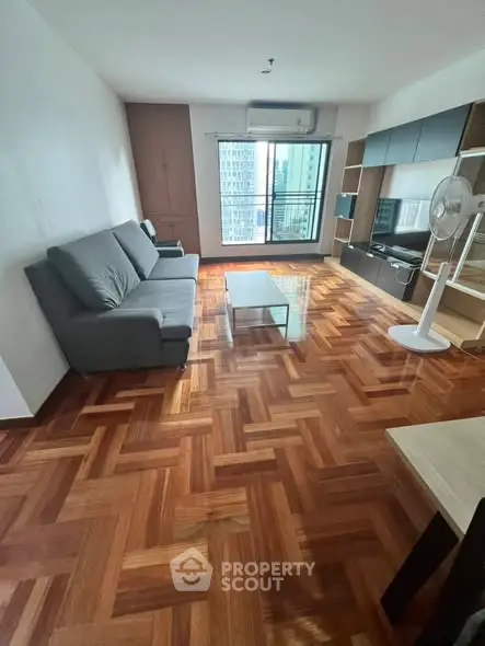 Spacious living room with wooden flooring and modern furniture in a high-rise apartment.