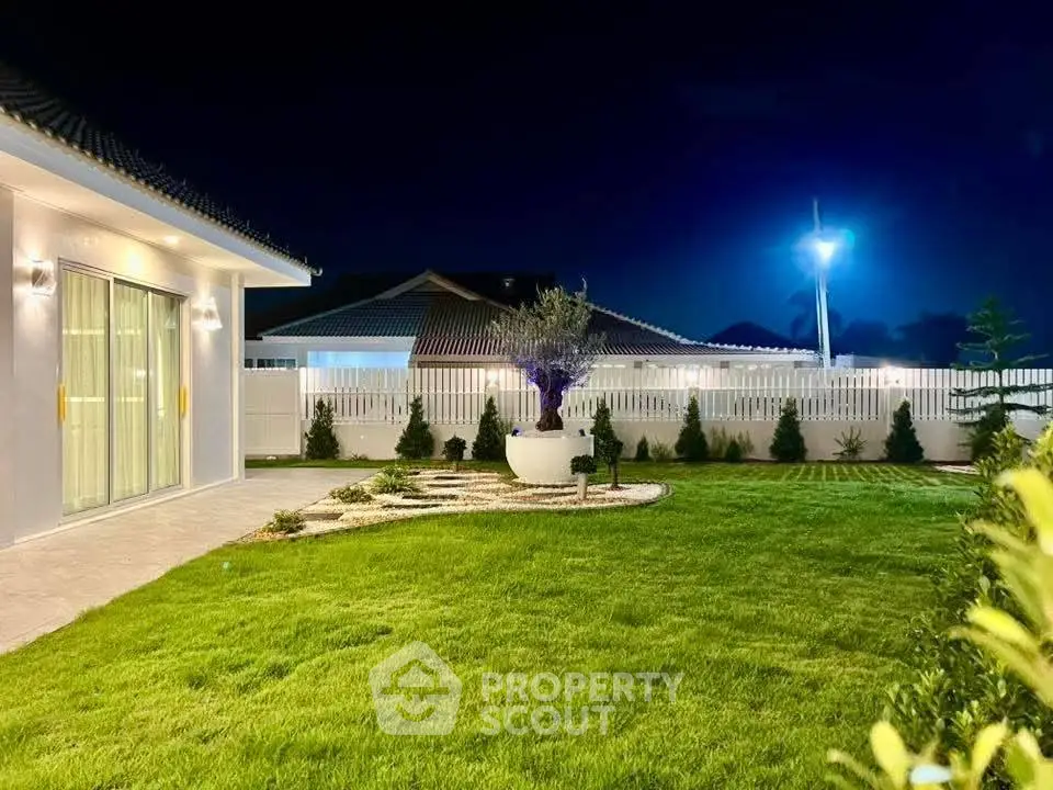 Stunning night view of a modern backyard with lush green lawn and elegant lighting.