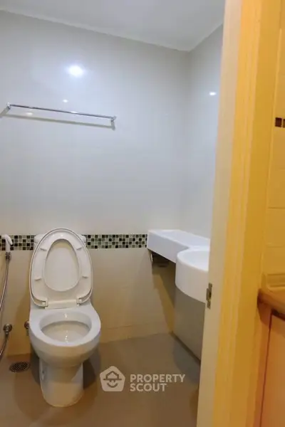 Modern bathroom with sleek fixtures and neutral tones, featuring a toilet and stylish sink.