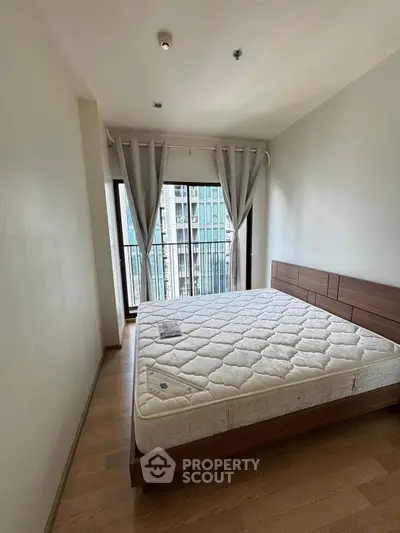 Spacious bedroom with large window and modern design in urban apartment.