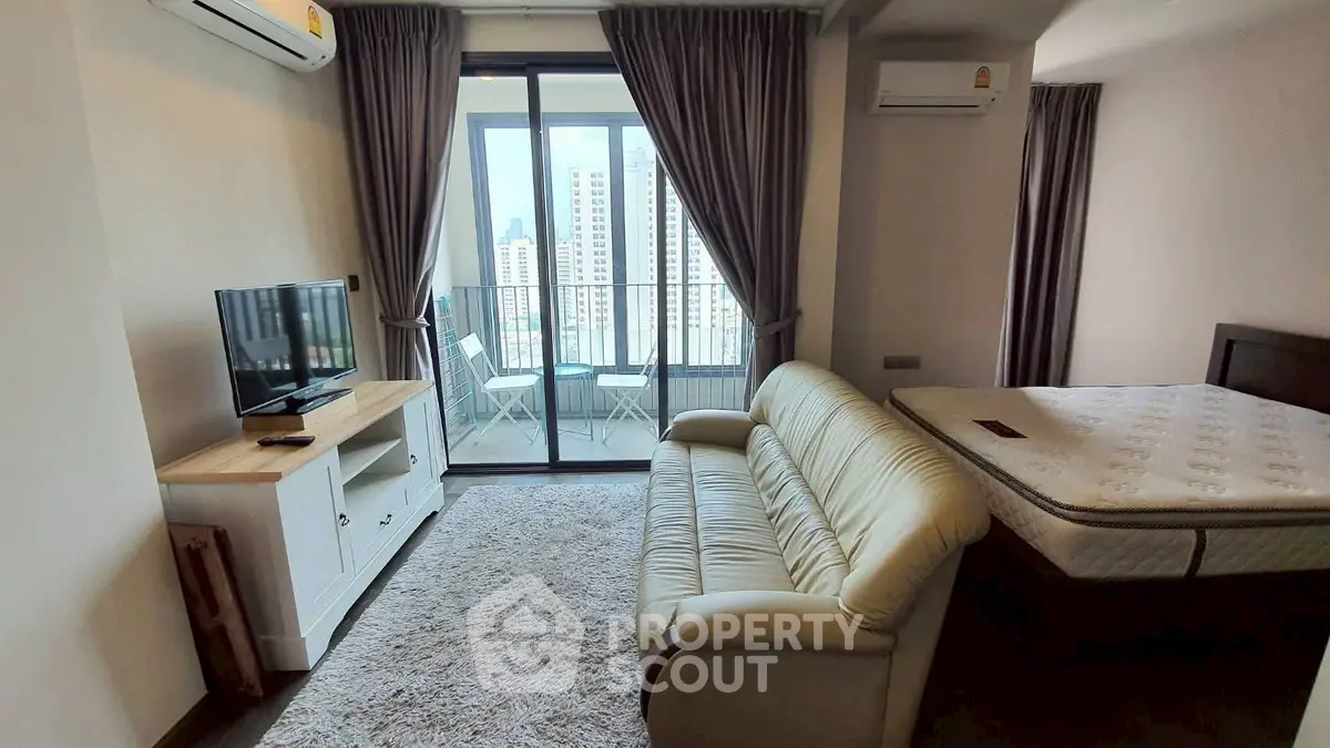 Modern studio apartment with balcony and city view, featuring cozy living area and comfortable furnishings.