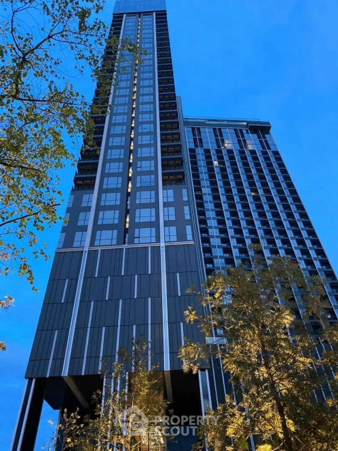 Stunning modern high-rise building with sleek architecture and illuminated facade at dusk.