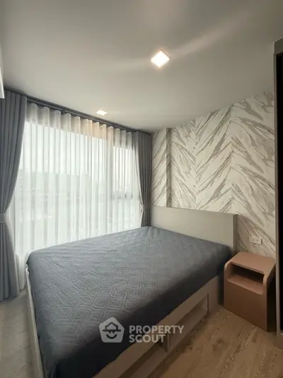 Modern bedroom with stylish accent wall and large window for natural light.