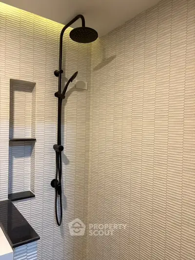 Modern bathroom with sleek black shower fixtures and textured wall tiles.