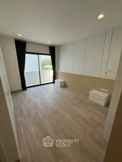 Spacious modern bedroom with large window and wooden flooring, perfect for natural light lovers.