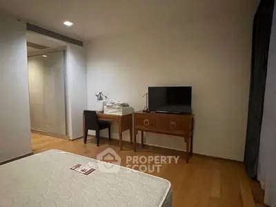 Cozy bedroom with wooden flooring, desk, and TV setup for modern living.