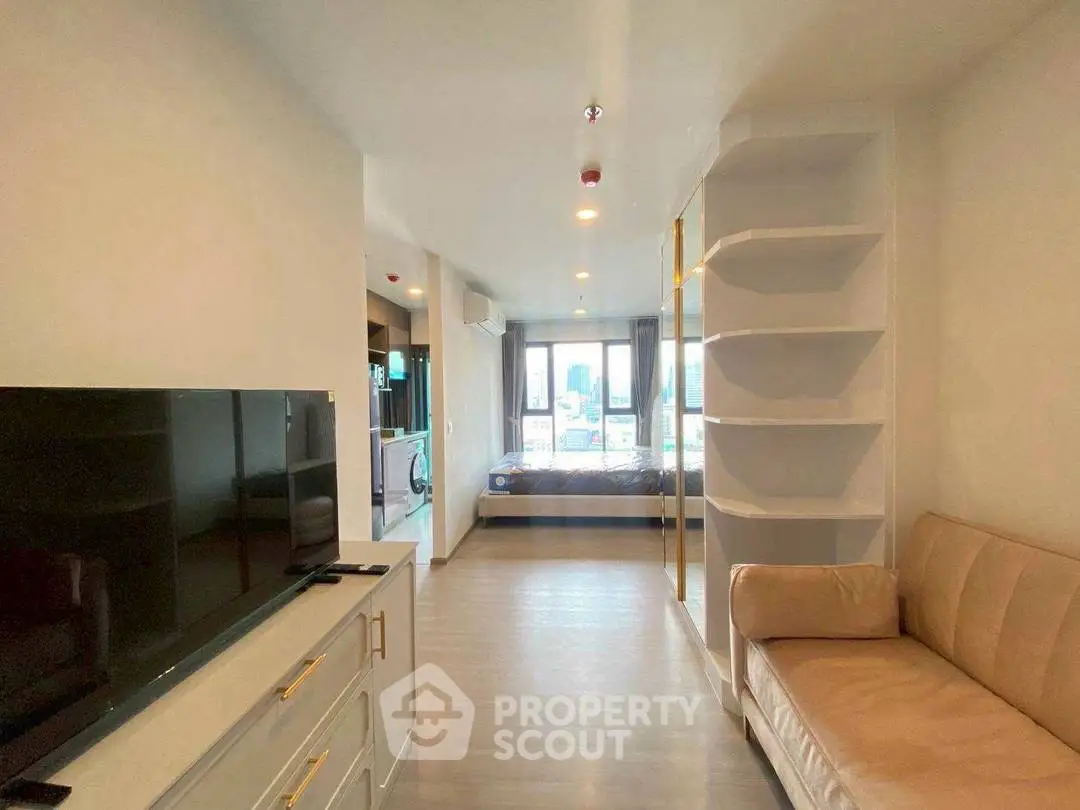 Modern open-plan living room with sleek furniture and large windows offering city views.