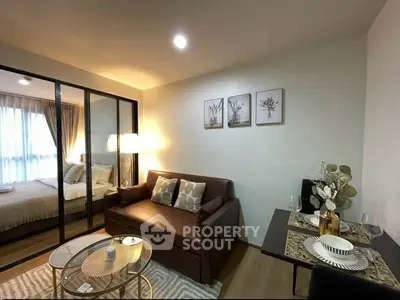 Modern living room with cozy sofa and stylish decor, adjacent to a bedroom with glass partition.