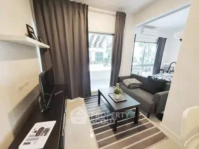 Modern living room with sleek furniture and large window offering natural light.