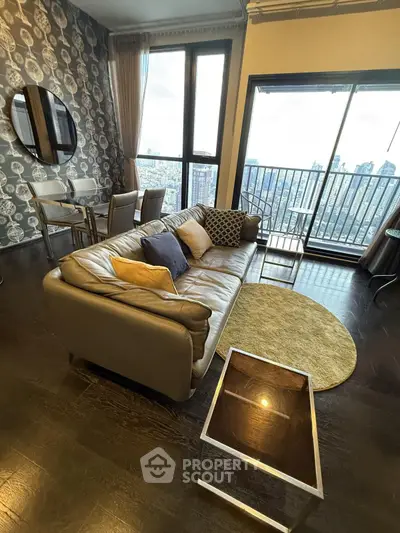 Stylish living room with city view, modern decor, and balcony access in high-rise apartment.