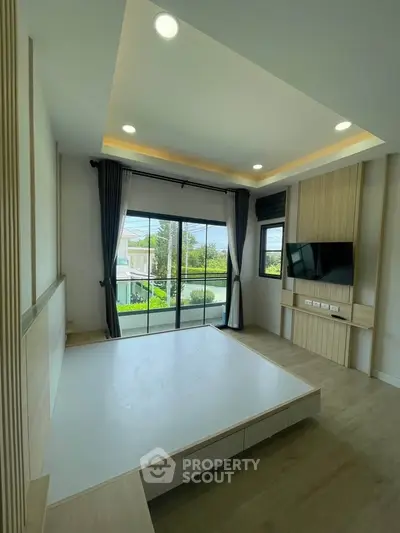 Modern bedroom with large windows and built-in TV, offering a serene view.