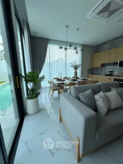 Modern open-plan living room with pool view, featuring elegant decor and natural light.