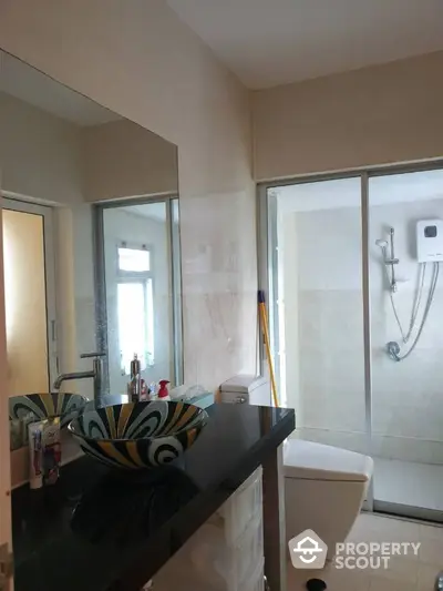 Modern bathroom with a glass-enclosed shower, stylish vessel sink, and neutral color palette offering a serene and elegant space.