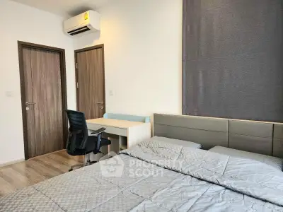 Modern bedroom with stylish decor, featuring a comfortable bed, desk, and air conditioning unit.