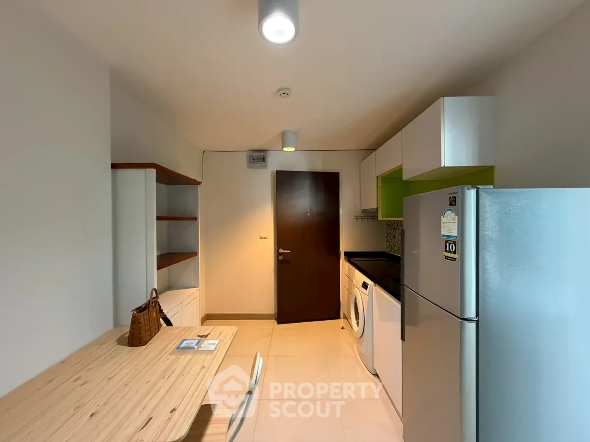 Modern kitchen with sleek appliances and wooden dining table in a stylish apartment.