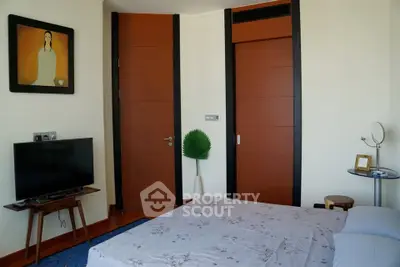 Modern bedroom with stylish decor and wooden accents, featuring a TV and unique artwork.