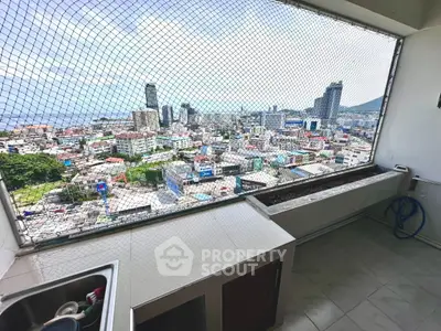 Stunning cityscape view from high-rise balcony with safety netting and tiled counter space.