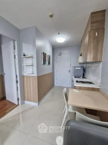 Modern compact kitchen with sleek cabinetry and dining area in a cozy apartment.