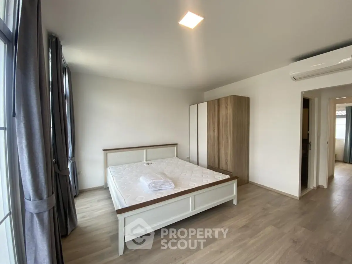 Spacious bedroom with modern decor and large windows for natural light