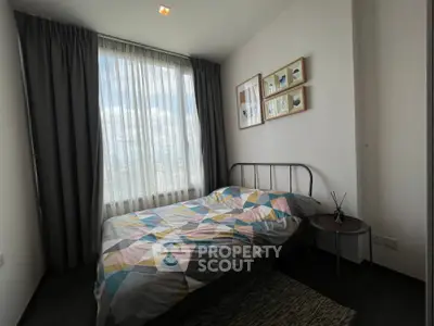 Cozy bedroom with modern decor and large window offering city views, perfect for urban living.