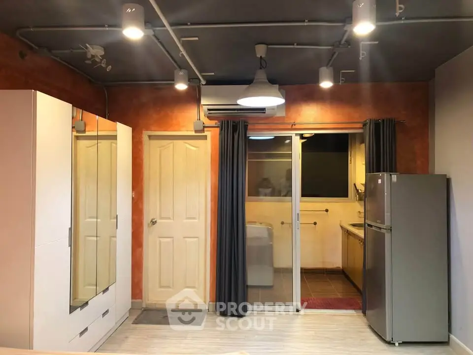 Modern apartment interior with stylish lighting and compact kitchen area.