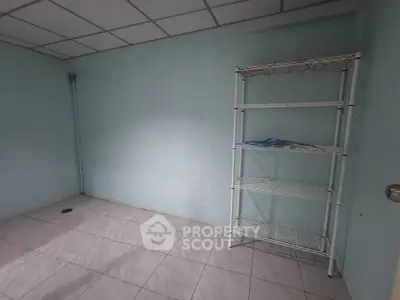 Minimalist empty room with tiled floor and metal shelving unit