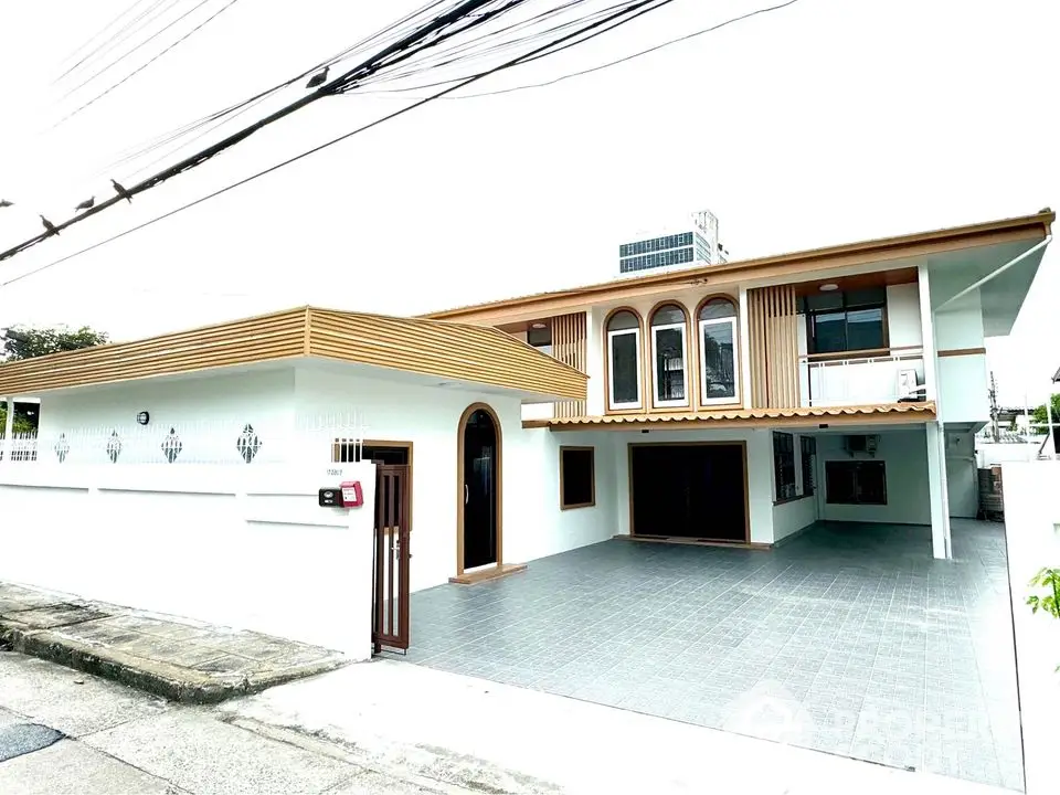 Spacious modern two-story house with large driveway and unique architectural design.