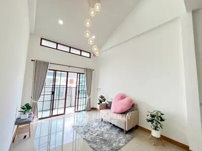 Bright living room with high ceiling, modern decor, and large windows for natural light.