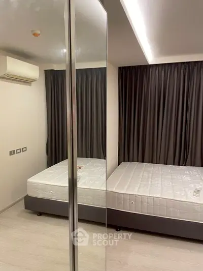 Modern bedroom with mirrored wardrobe and air conditioning in a stylish apartment.