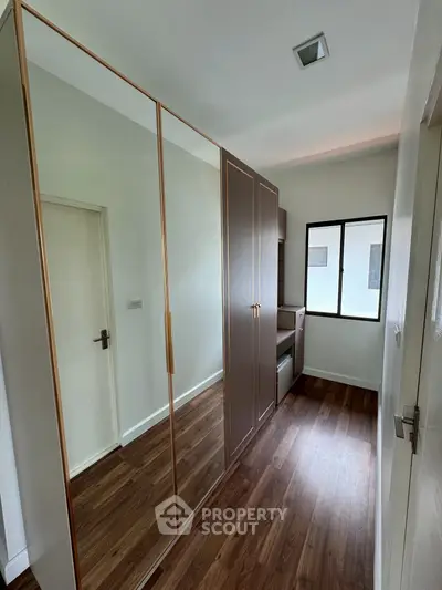 Modern bedroom with sleek wooden flooring and built-in wardrobe, offering ample storage space and natural light.
