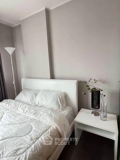 Cozy bedroom with modern decor and minimalist design, featuring a white bed and stylish nightstand.