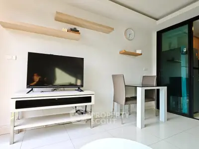 Modern living room with sleek TV setup and dining area in a stylish apartment.
